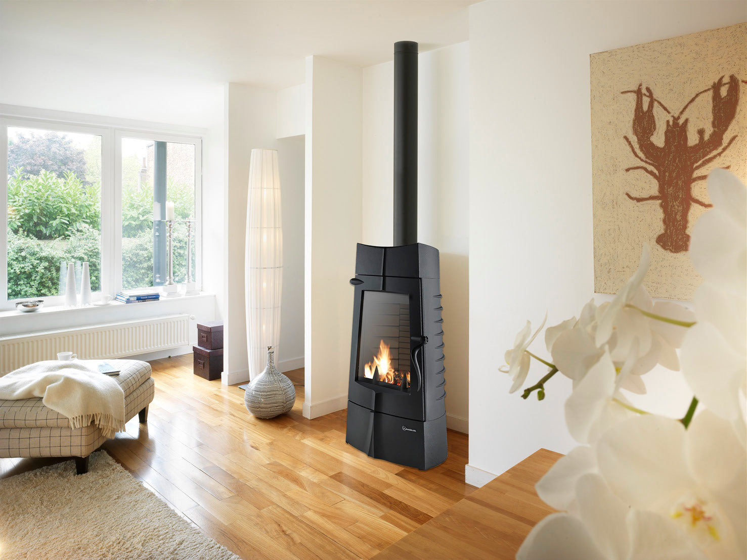 Chamane antracit färgad fristående gjutjärnskamin. Installation av kamin, fristående kamin i gjutjärn med skorsten i stål. Håller jämn och behaglig värme inomhus en lång tid även efter elden har slocknat i braskaminen.